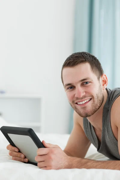 Portrait of a man using a tablet computer while lying on his bel — Stock Photo, Image
