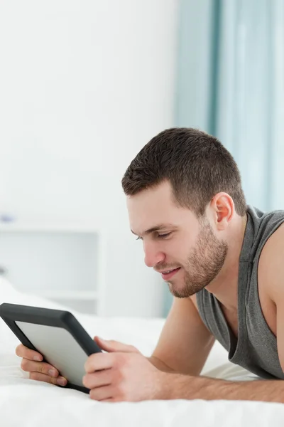 Podobizna mladého muže pomocí tabletového počítače vleže na h — Stock fotografie