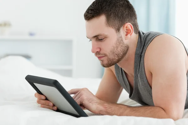 잘생긴 남자 그의 배꼽에 누워 있는 동안 태블릿 컴퓨터를 사용 하 여 — 스톡 사진