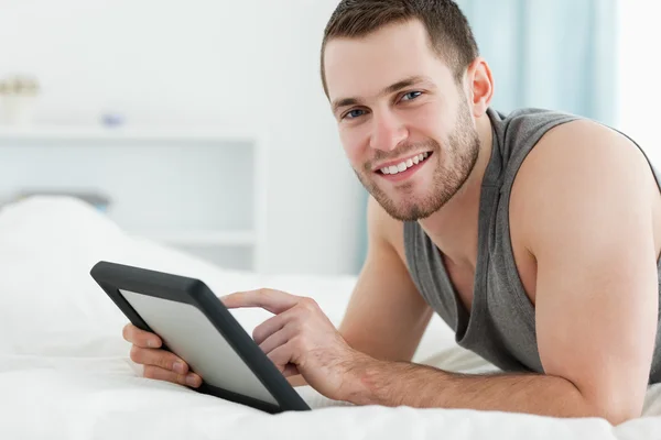 Χαμογελαστός άνθρωπος χρησιμοποιώντας έναν υπολογιστή δισκίο, ενώ βρίσκεται στην κοιλιά του — Φωτογραφία Αρχείου