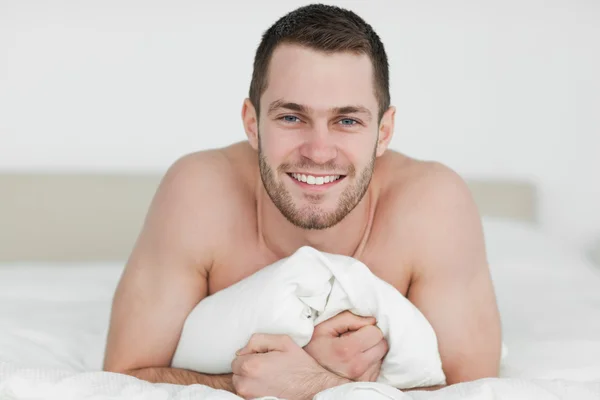 Улыбающийся мужчина лежит на кровати — стоковое фото