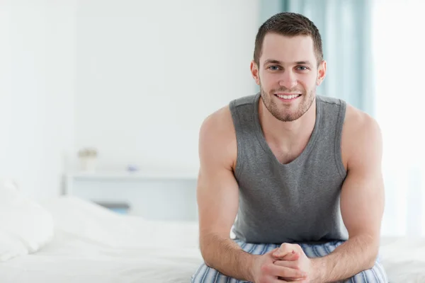 Uśmiechnięty mężczyzna siedzi na łóżku — Zdjęcie stockowe