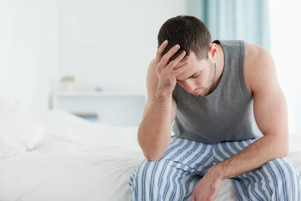 Smutný muž, sedící na posteli — Stock fotografie