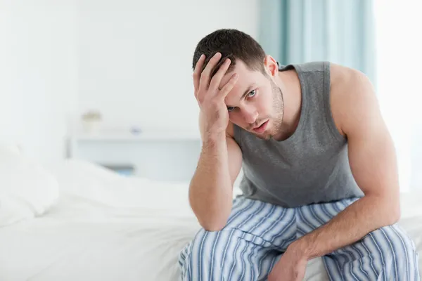 Tired man sitting on his bed — Stock Photo, Image