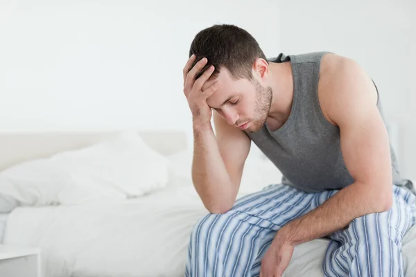 Exhausted man sitting on his bed — Stock Photo, Image