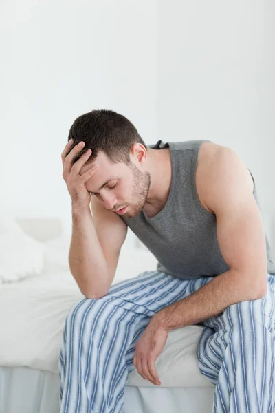 Portrait of an exhausted man sitting on his bed — Stock Photo, Image