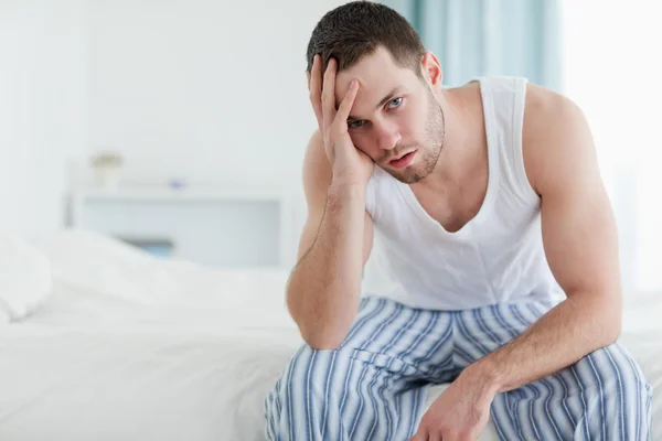 Przygnębiony człowiek siedzi na łóżku — Zdjęcie stockowe