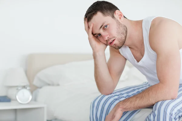 Больной человек сидит на кровати — стоковое фото