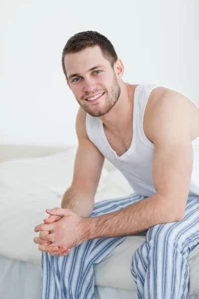 Πορτρέτο του ένας χαμογελαστός νεαρός άνδρας κάθεται στο κρεβάτι του — Φωτογραφία Αρχείου
