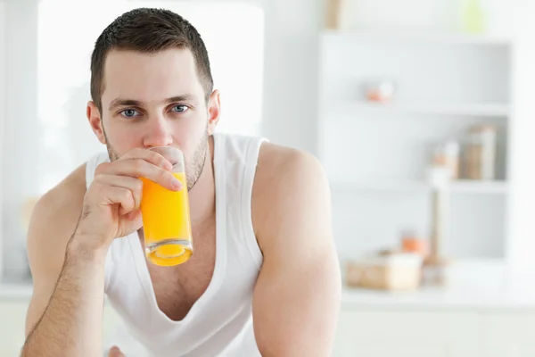 Homem bonito bebendo suco de laranja — Fotografia de Stock