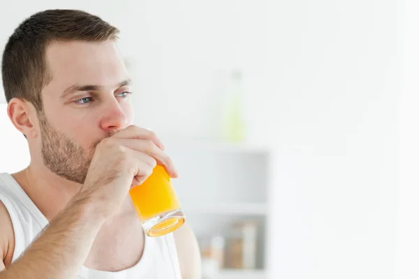 Retrato de um homem encantado bebendo suco de laranja — Fotografia de Stock