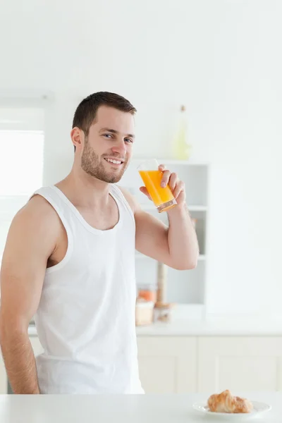 Retrato de um homem sorridente bebendo suco de laranja — Fotografia de Stock