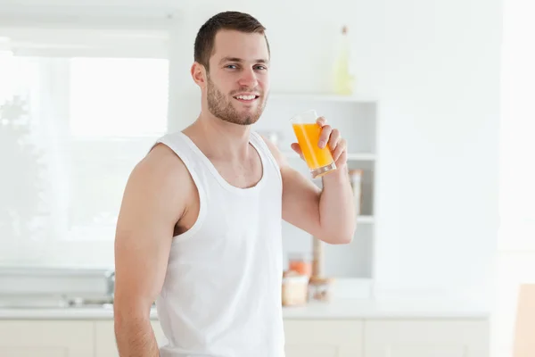 Улыбающийся человек пьет апельсиновый сок — стоковое фото