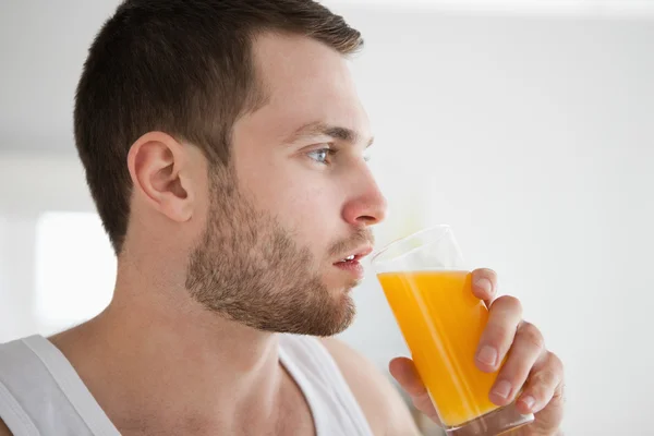 Närbild på en frisk man dricka apelsinjuice — Stockfoto