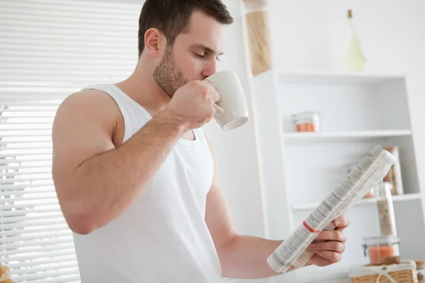 Young man drinking coffee while reading the news — Stock Photo, Image