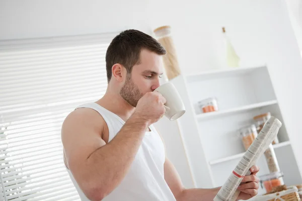 Young man drinking tea while reading the news — Stock Photo, Image