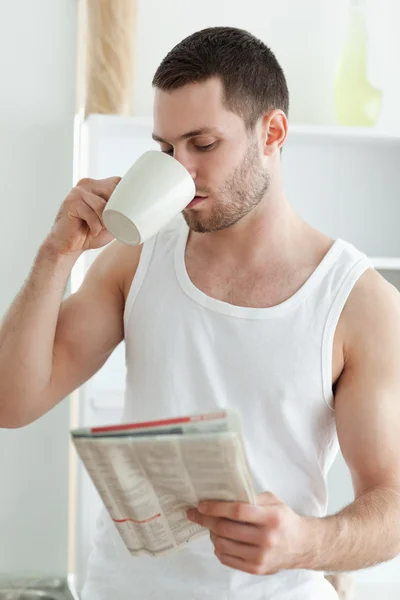 Porträtt av en ung man dricka te medan du läser nyheter — Stockfoto