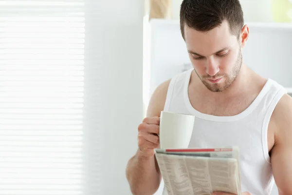 Улыбающийся мужчина пьет кофе во время чтения новостей — стоковое фото