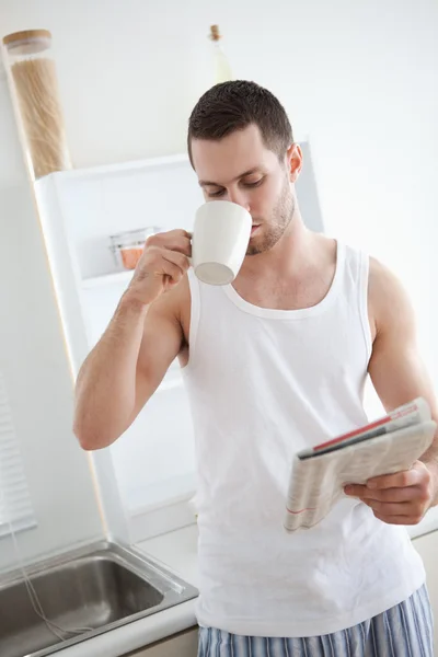 Portrait of a good looking man drinking tea while reading the ne — Stock Photo, Image