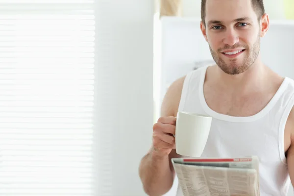 Dobře vypadající muž pití čaje při čtení zprávy — Stock fotografie