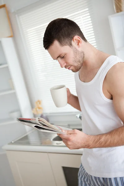 Portrait of a good looking man drinking coffee while reading the — Stock Photo, Image