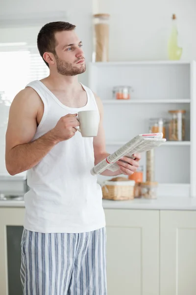 Portrait of a sports man drinking tea while reading the news — Stock Photo, Image