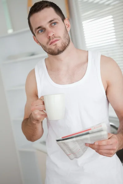 Portrait of a healthy man drinking tea while reading the news — Stock Photo, Image