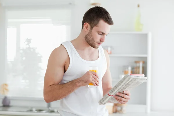 オレンジ ジュースを飲みながらニュースを読む男 — ストック写真