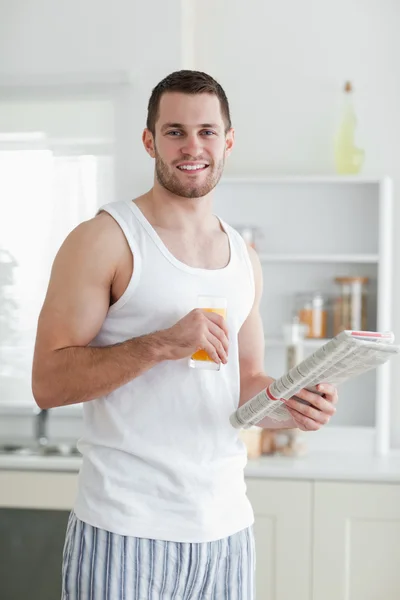 Portrait of a smiling man drinking orange juice while reading th — Stock Photo, Image