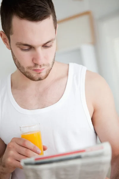 Портрет красивого человека, пьющего апельсиновый сок во время чтения — стоковое фото