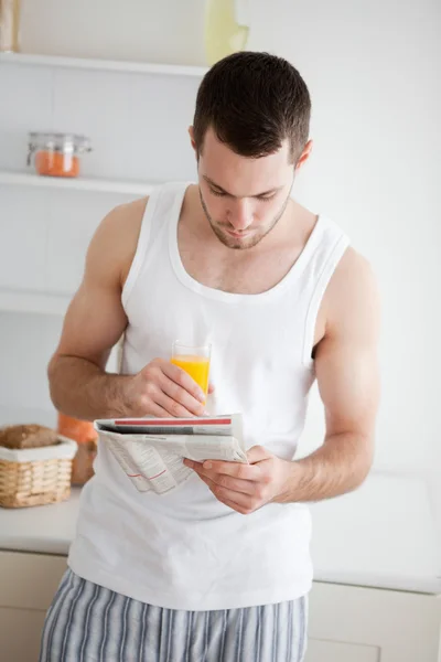 Portrait of a man reading the news while drinking orange juice — Stock Photo, Image
