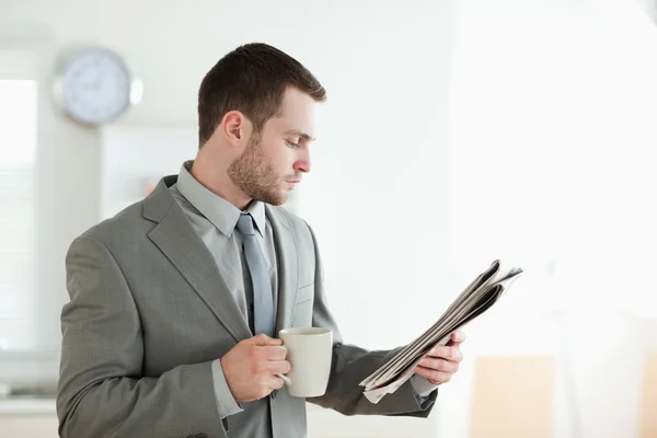 Businessman drinking tea while reading the news — Stock Photo, Image