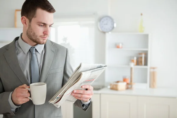 Empresario bebiendo café mientras lee las noticias —  Fotos de Stock