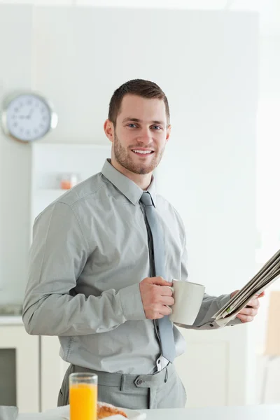 Portrait of a smiling businessman reading the news while having — Stock Photo, Image