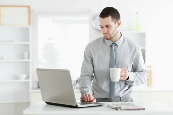 Empresário usando um laptop enquanto bebe café — Fotografia de Stock