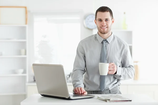 Businessman using a notebook while drinking coffee — Stock Photo, Image