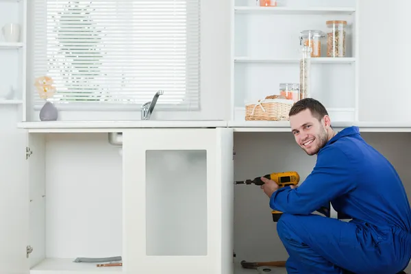 Smiling handyman fixing a door — Stock Photo, Image