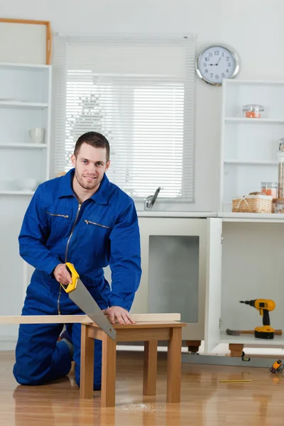 Portrait of a smiling handyman cutting a wooden board — Stock Photo, Image