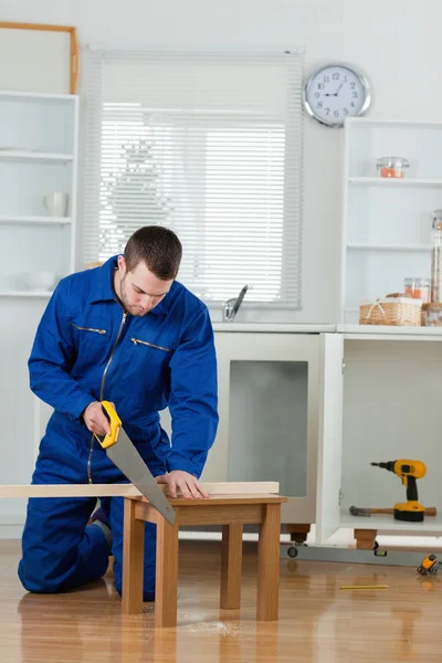 Portrait of a handsome handyman cutting a wooden board — Stock Photo, Image