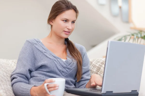 Γυναίκα χρησιμοποιώντας ένα φορητό υπολογιστή ενώ έχοντας ένα καφέ — Φωτογραφία Αρχείου