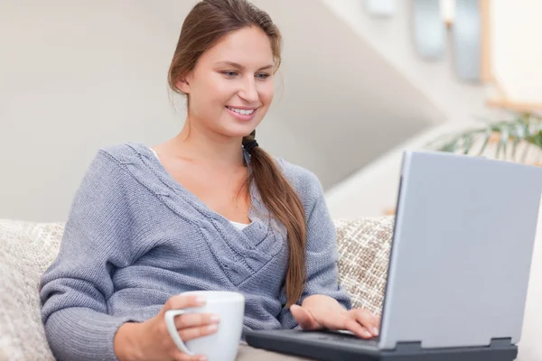 Жінка використовує ноутбук, маючи чай — стокове фото