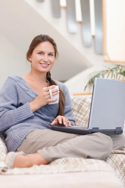 Retrato de uma mulher usando um laptop enquanto toma um café — Fotografia de Stock