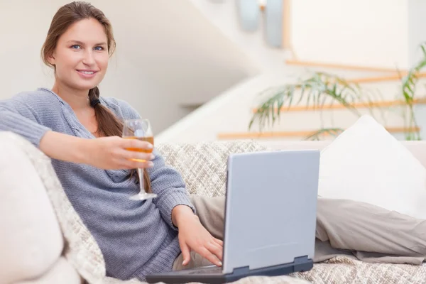 Γυναίκα έχοντας ένα ποτήρι κρασί, ενώ χρησιμοποιώντας το laptop — Φωτογραφία Αρχείου