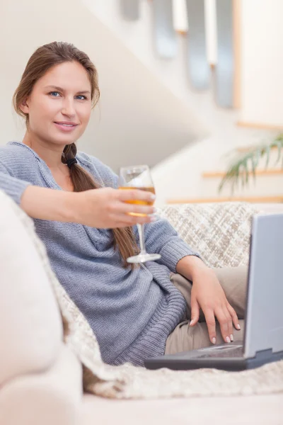 Porträt einer Frau bei einem Glas Wein, während sie ihren Lapto benutzt — Stockfoto