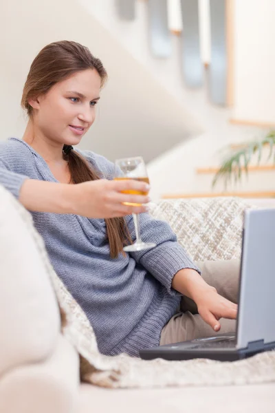 Retrato de uma mulher tomando um copo de vinho branco enquanto a usa — Fotografia de Stock