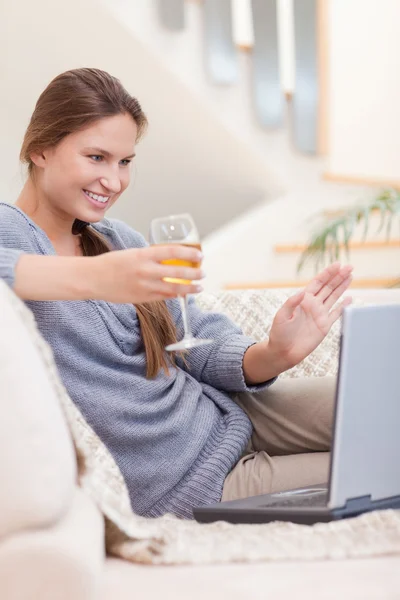 Retrato de una mujer tomando una copa de vino blanco durante un video —  Fotos de Stock