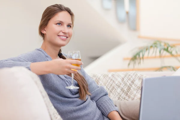 Vrouw met een glas wijn tijdens het gebruik van haar notitieblok — Stockfoto