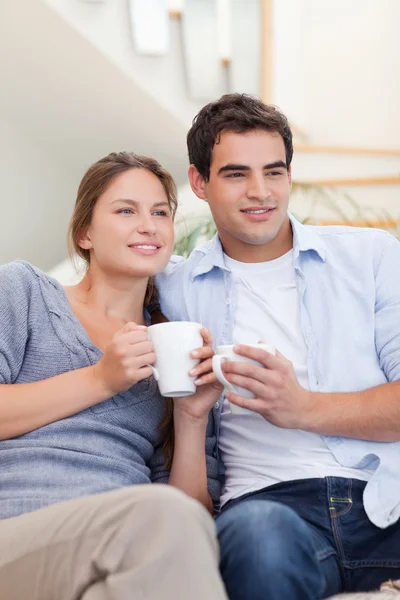 Retrato de um casal bebendo café enquanto assiste TV — Fotografia de Stock