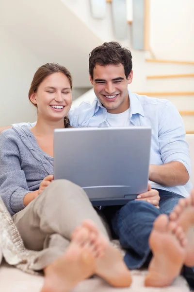Porträt eines Paares, das einen Laptop benutzt, während es auf einem Sofa liegt — Stockfoto