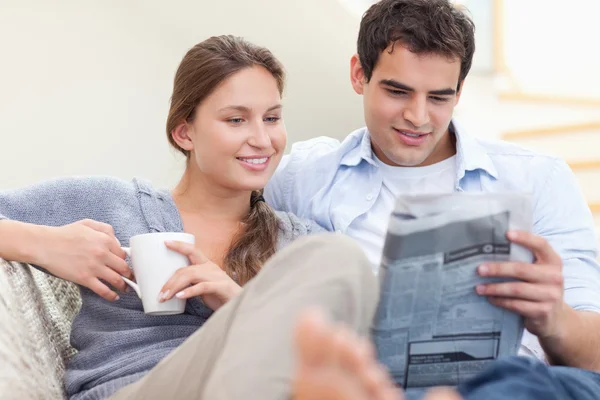 Paar liest Nachrichten, während es auf dem Sofa liegt — Stockfoto